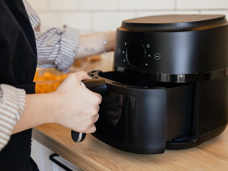 Airfryer sepetini cihazın içine yerleştiren kişi
