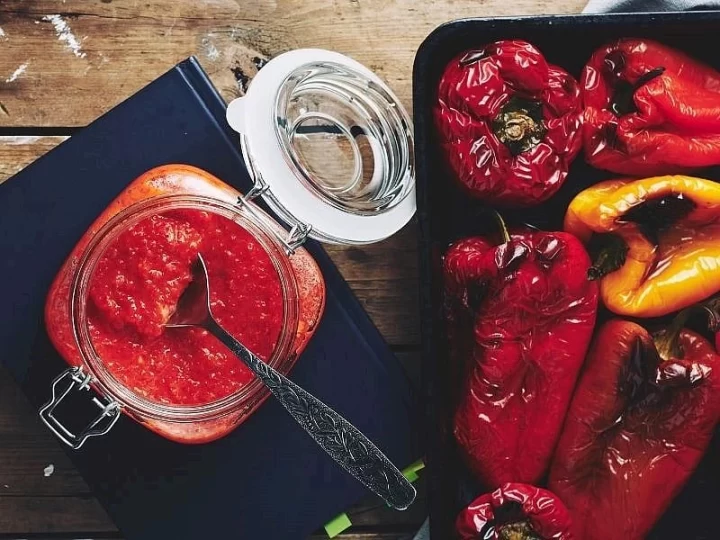Kavanozda ajvar sos ve yanında közlenmiş kırmızı biberler