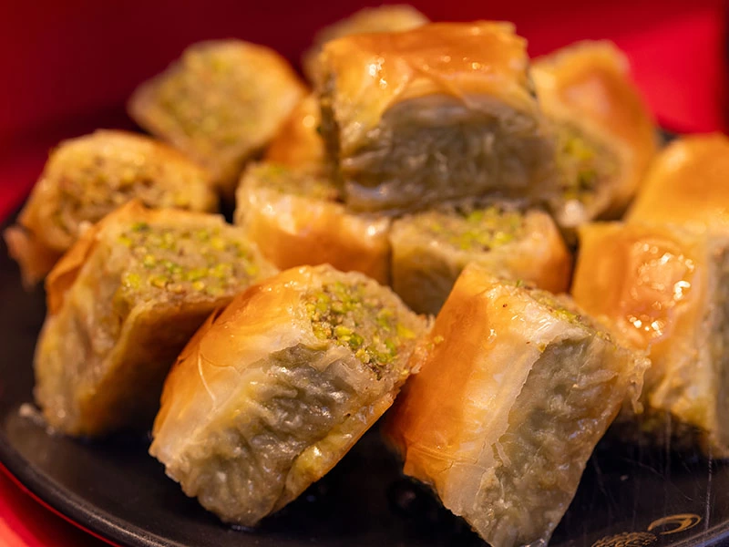 Koyu renk tabakta servis edilmiş farklı şekillerde baklava dilimleri