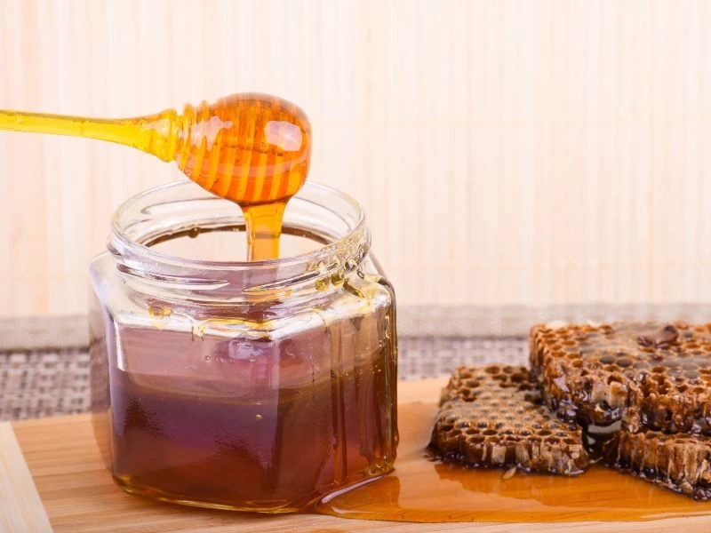 Bal kavanozu, bal kaşığı ve bal peteği parçaları