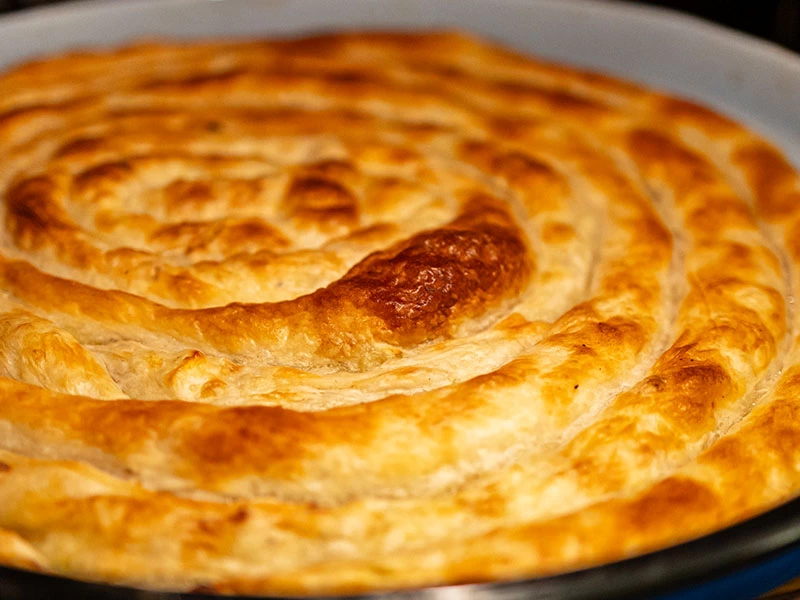 Fırın tepsisinde altın sarısı renkte kızarmış börek