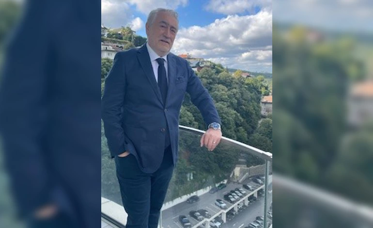Bilge Özdemir, açık havada bir balkon korkuluğunun yanında duruyor.