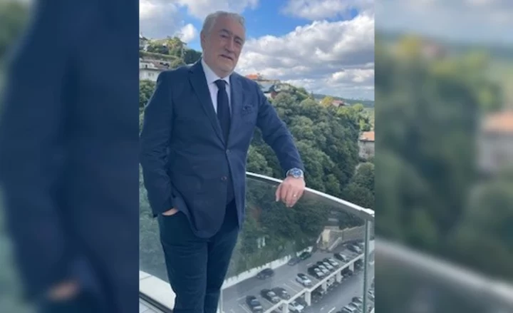Bilge Özdemir, açık havada bir balkon korkuluğunun yanında duruyor.