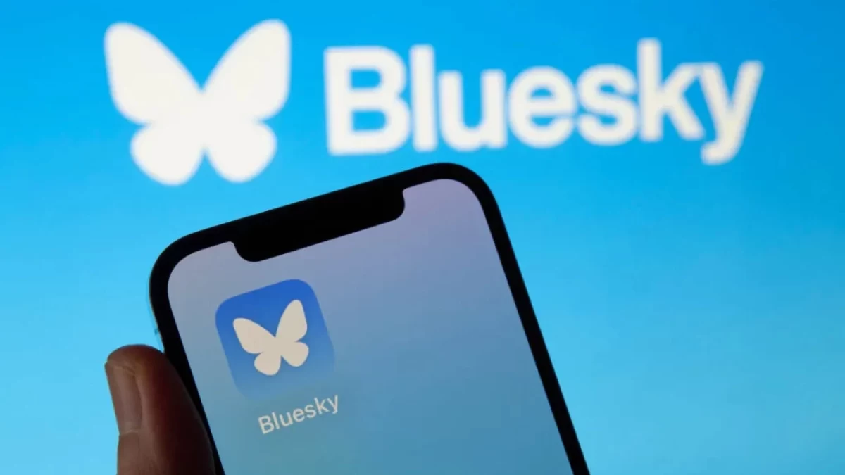 Bluesky logosunun önünde, uygulama simgesi açık bir akıllı telefon