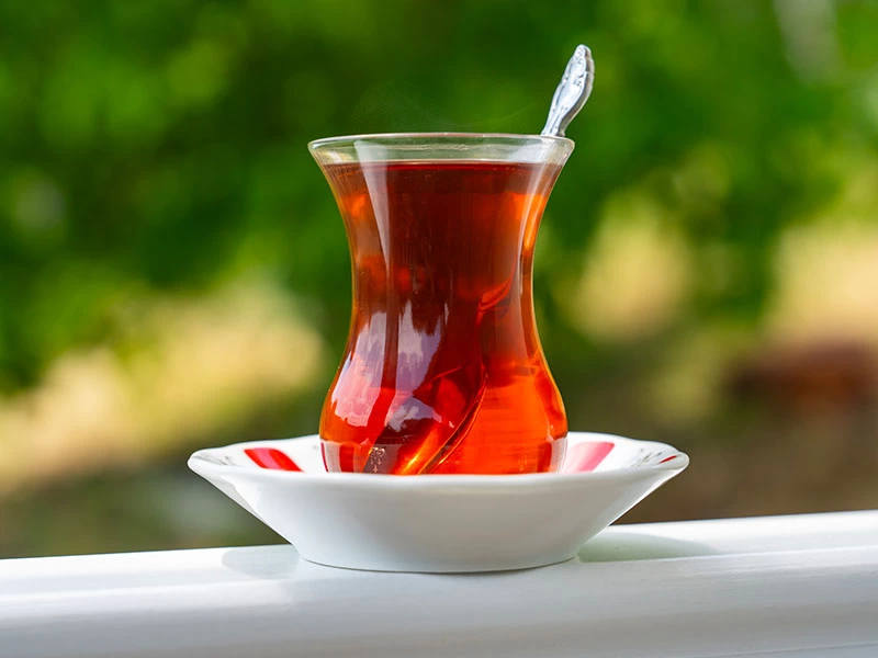 Beyaz tabakta kaşık bulunan bir bardak çay