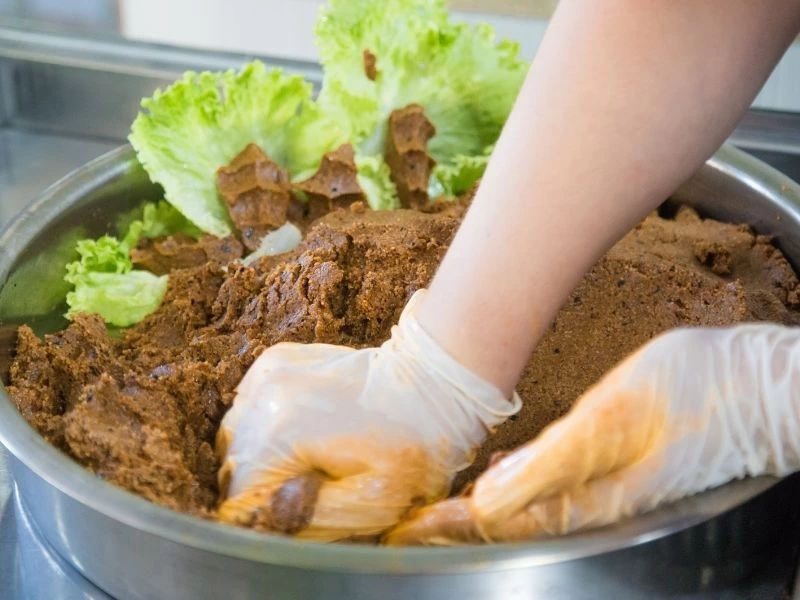 Eldivenli eller geniş bir kapta çiğ köfte harcını yoğuruyor