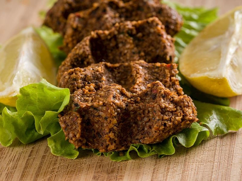 Marul ve limon dilimleri üzerinde servis edilen sıkım çiğ köfte