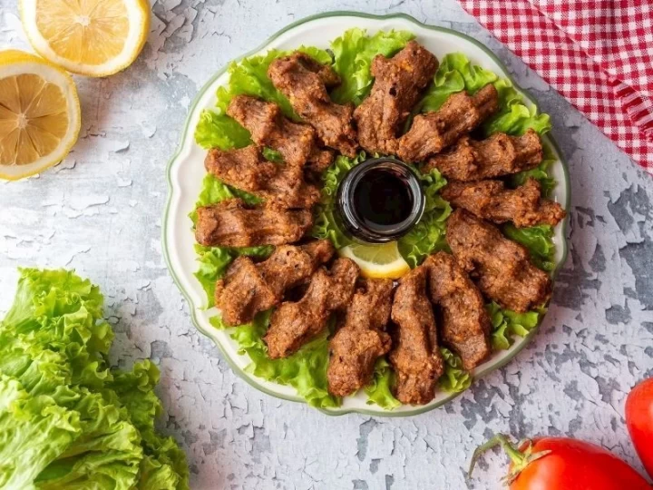 Yeşilliklerle ve limon dilimleriyle servis edilen çiğ köfte