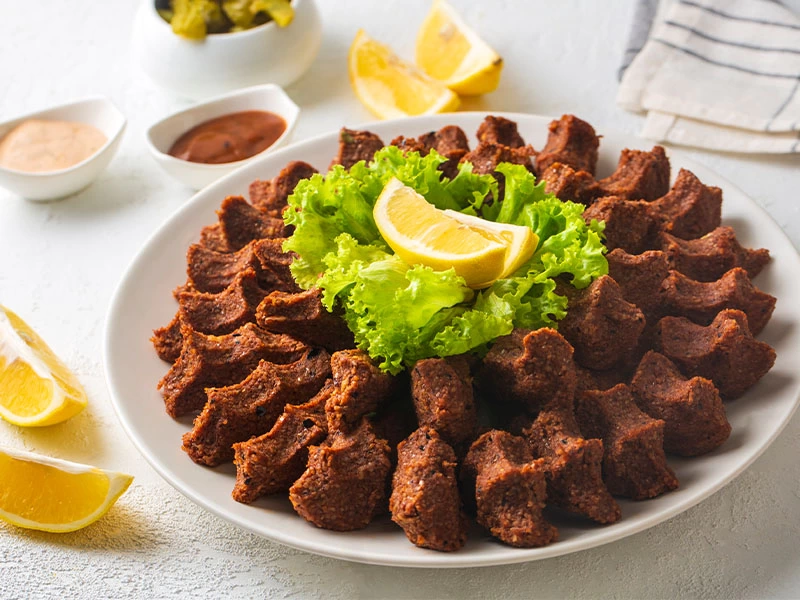 Limon ve marulla süslenmiş tabakta çiğ köfteler