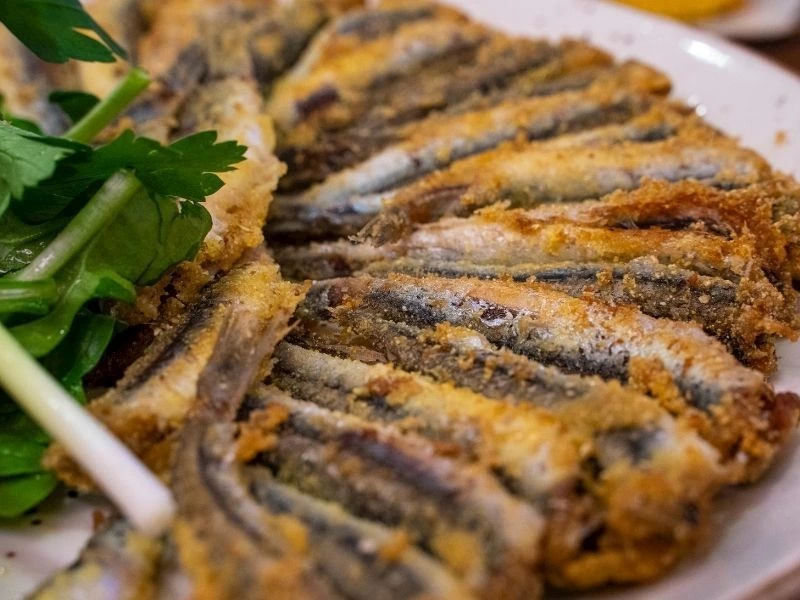 Tabakta kızarmış hamsi tava ve yanında yeşillikler