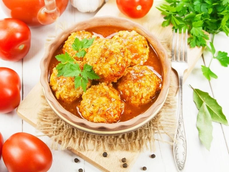 Domates sosunda pişmiş köfteler maydanozla servis edilmiş