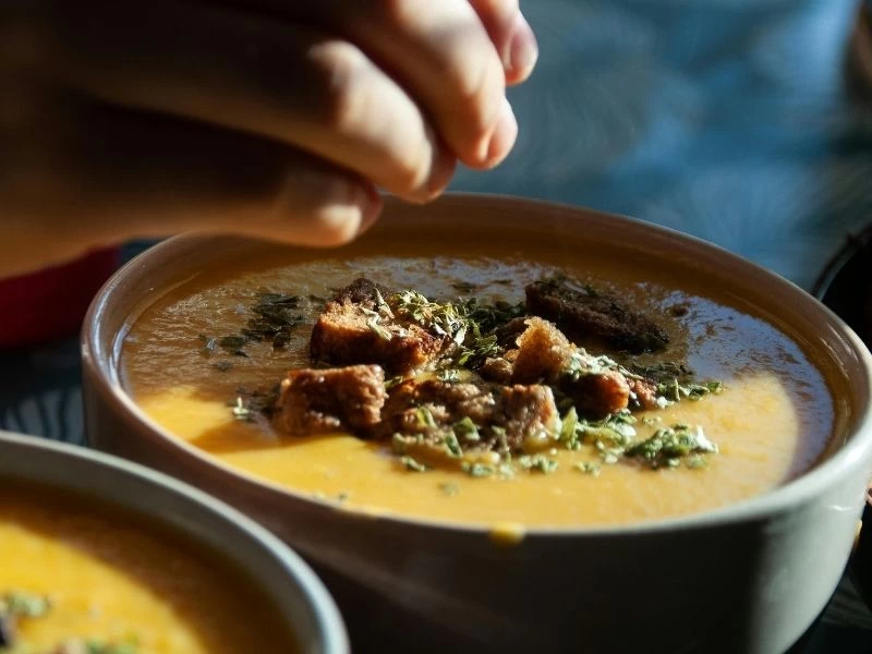 Üzerine ekmek parçaları ve otlar serpilmiş çorba