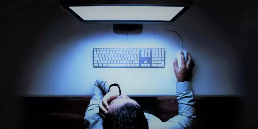 Bir kişinin bilgisayar ekranı başında gözlüklerini düzelttiği çalışma ortamı