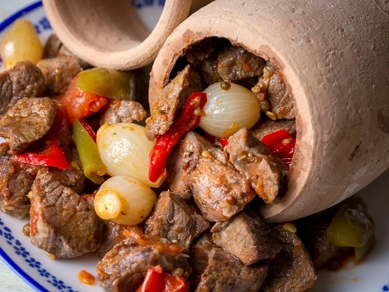 Toprak kap içindeki et parçaları, soğan ve biberlerle testi kebabı