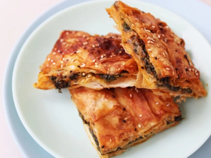 Tabakta servis edilen, ıspanaklı içi görünen kızarmış börek dilimleri