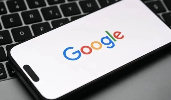 Google logosunun yer aldığı bir akıllı telefon, klavye üzerinde duruyor