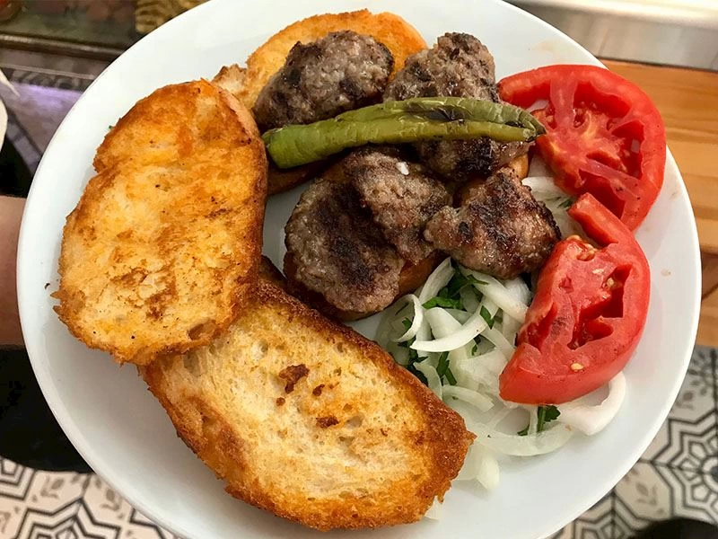 Kızarmış ekmek ve köfteler, yanında domates, biber ve soğan