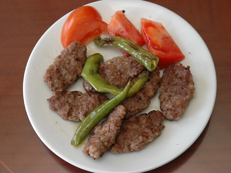 Tabakta köfteler, yeşil biber ve domates dilimleri