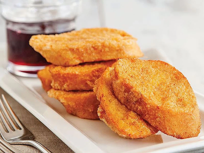 Beyaz tabakta üst üste servis edilmiş kızarmış yumurtalı ekmek dilimleri