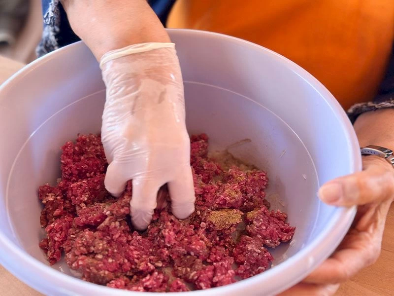 Eldivenli elle bir kapta köfte harcının yoğrulması