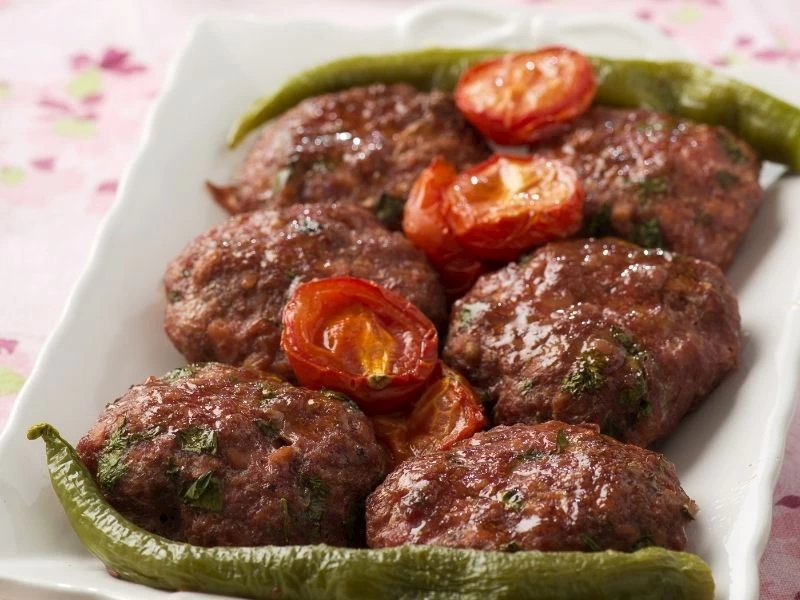 Domates ve yeşil biberle servis edilen kızarmış köfteler