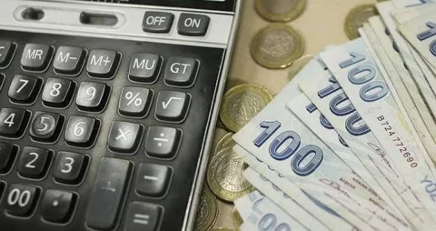 Hesap makinesi yanında 100 euro banknotları ve madeni paralar
