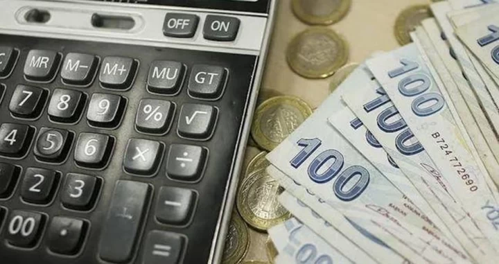 Hesap makinesi yanında 100 euro banknotları ve madeni paralar