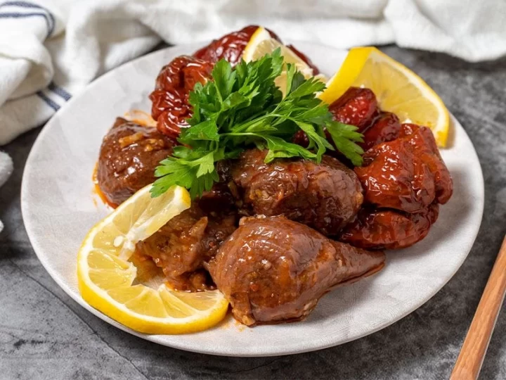 Maydanoz ve limonla servis edilen kuru dolma tabağı