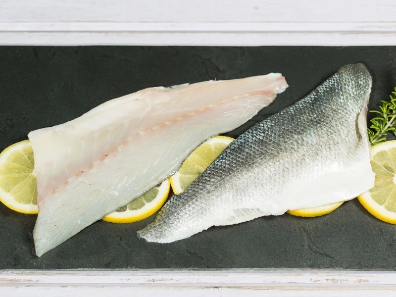 Kesilmiş levrek filetoları ve limon dilimleri