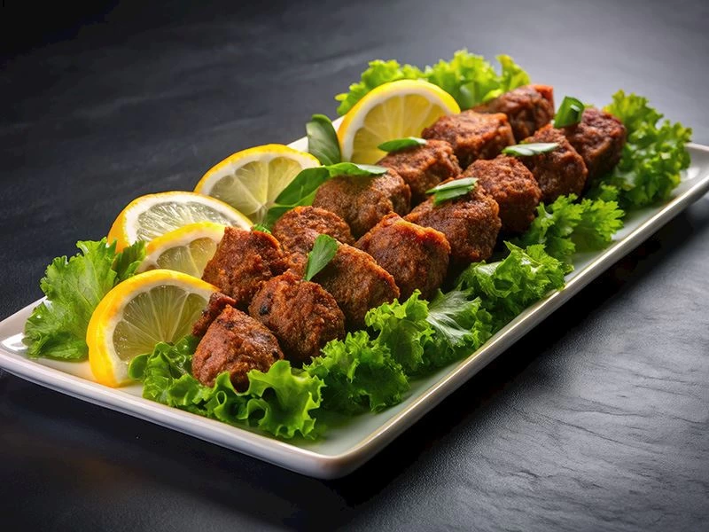 Limon dilimleri ve yeşilliklerle sunulan çiğ köfte