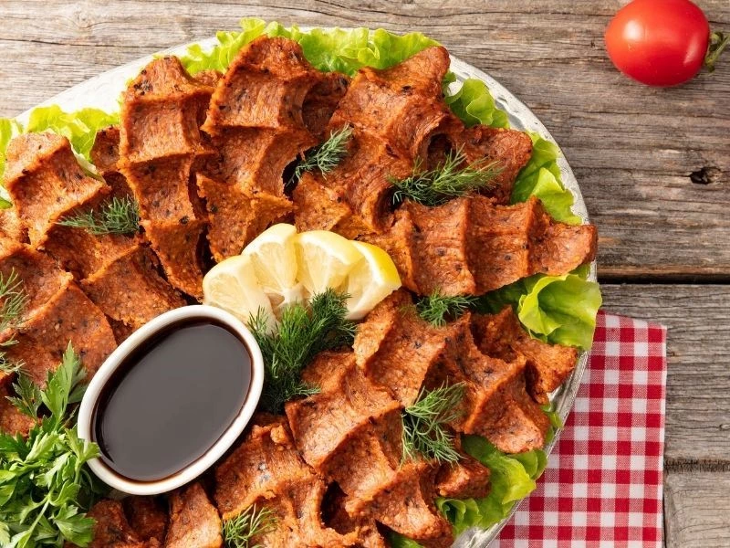 Limon ve yeşilliklerle servis tabağına alınmış çiğ köfteler