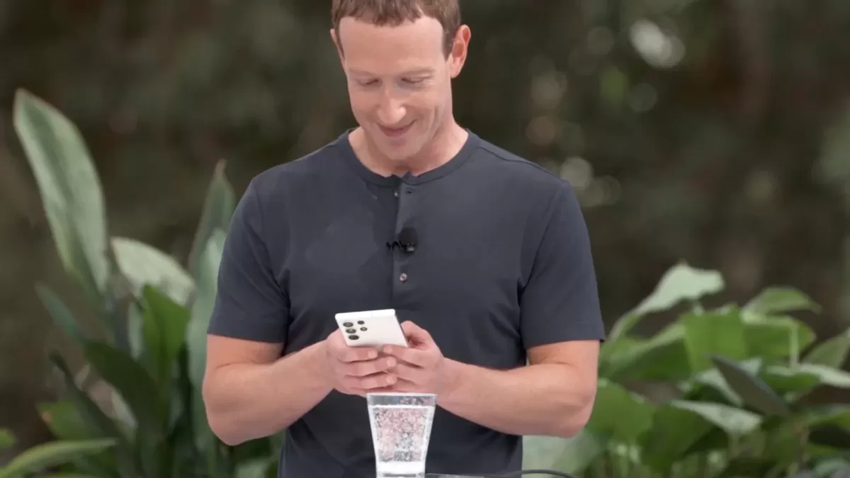 Mark Zuckerberg elindeki akıllı telefona bakıyor