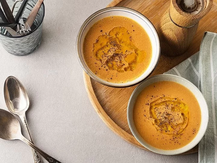 Ahşap tepsi üzerinde iki kâsede servis edilen mercimek çorbası