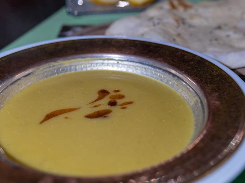 Koyu renkli tabakta servis edilen mercimek çorbası