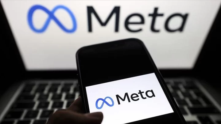 Bir akıllı telefon ekranında Meta logosu, arka planda dizüstü bilgisayarda Meta işareti
