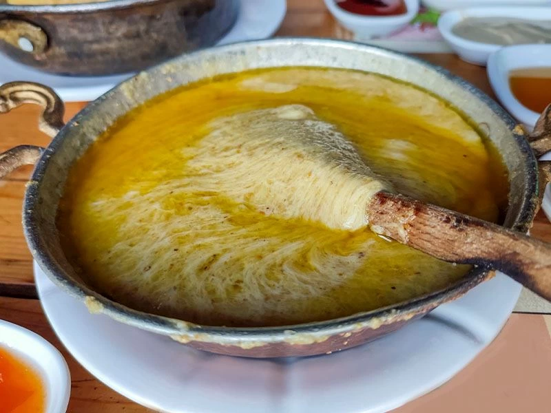 Tavada uzayan peynirli mıhlama ve tahta kaşık