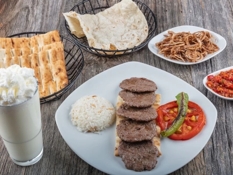 Pide ve pilav eşliğinde servis edilen köfteler, yanında ayran ve salata