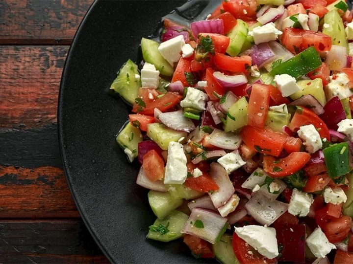Siyah tabakta domates, salatalık, soğan ve peynirle hazırlanmış salata