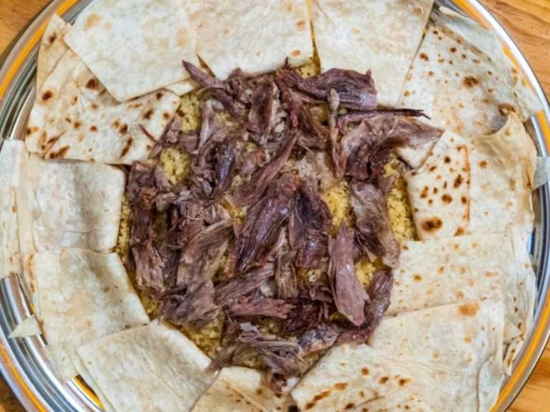 Yufkaların üzerinde servis edilen kaz eti ve bulgur pilavı