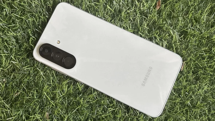 Çimenlerin üzerinde arka yüzü görünen beyaz Samsung akıllı telefon