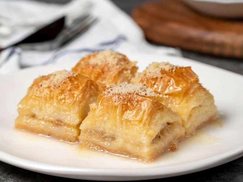 Tabakta şerbet içinde duran dilimlenmiş baklava