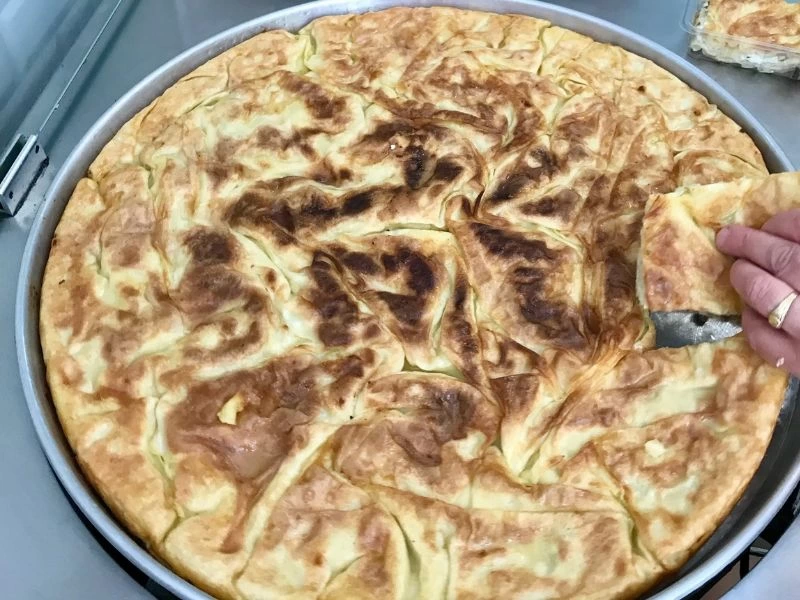 Pişmiş su böreği, yuvarlak sinide dilimlenirken
