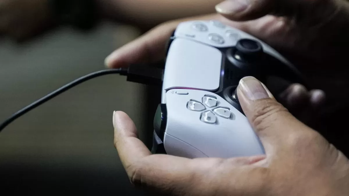 Bir kişinin elinde tuttuğu beyaz PlayStation kontrolcüsü