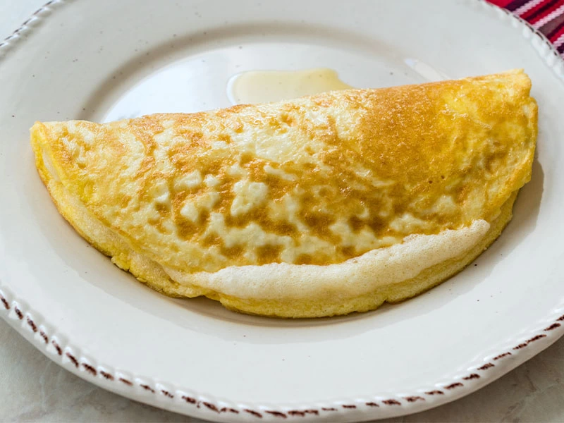 Beyaz tabakta servis edilen katlanmış omlet