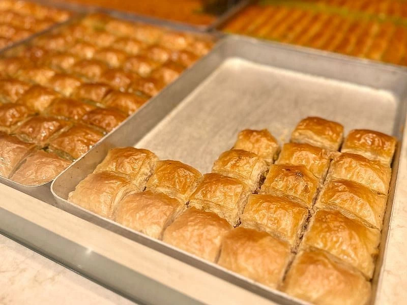 Metal tepsilerde sıralanmış kızarmış baklavalar