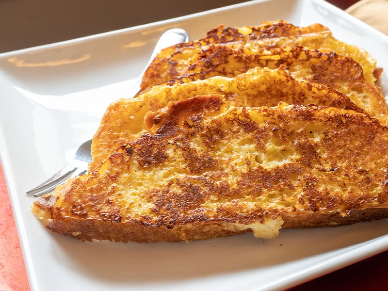Beyaz tabakta yan yana duran kızarmış yumurtalı ekmek dilimleri