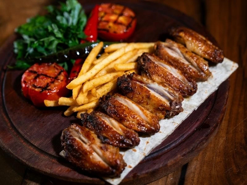 Patates kızartması ve sebzelerle servis edilen dilimlenmiş tavuk
