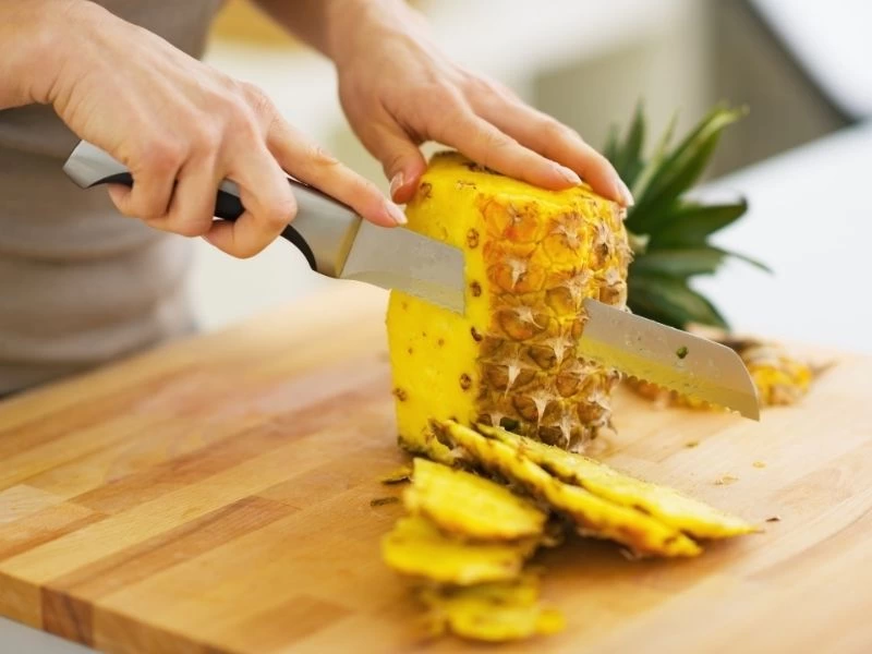 Kesme tahtasında ananas hazırlayan eller