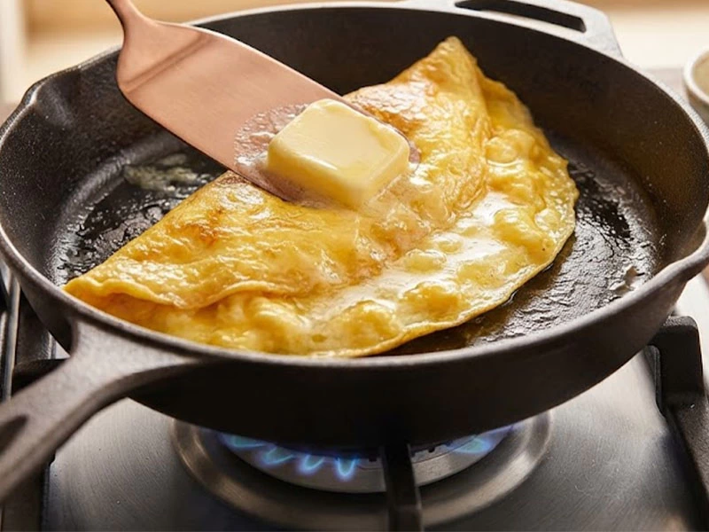 Tereyağı parçası yumurtalı omletin üzerine bırakılıyor