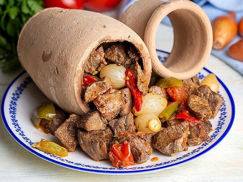Toprak testiden tabağa dökülmüş etli ve sebzeli kebap